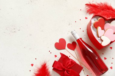 Bir şişe kırmızı şarap, hediye kutusu ve beyaz grunge arka planda kalp şeklinde kurabiyeler. Sevgililer Günü kutlaması