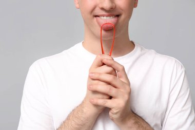 Gri arka planda dil kazıyıcı kullanan adam, yakın plan.