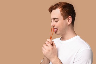 Bej arka planda dil kazıyıcısı olan genç bir adam.