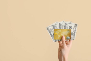 Bej arkaplanda kredi kartı ve dolar banknotları olan bir kadın
