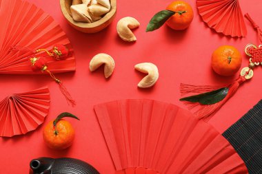 Kağıt fanlar, fal kurabiyeleri, mandalinalar ve kırmızı arka planda Çin sembolleri olan kompozisyon. Yeni yıl kutlaması