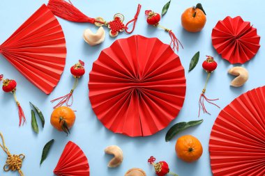 Mavi arka planda kağıt yelpaze, mandalina ve Çin sembolleri olan kompozisyon. Yeni yıl kutlaması