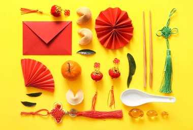 Sarı arka planda kağıt yelpaze, mandalina ve Çin sembolleri olan kompozisyon. Yeni yıl kutlaması