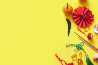 Sarı arka planda kağıt yelpaze, mandalina ve Çin sembolleri olan kompozisyon. Yeni yıl kutlaması