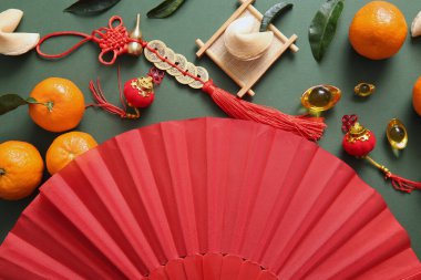 Yeşil arka planda kağıt yelpaze, mandalina ve Çin sembolleri olan kompozisyon. Yeni yıl kutlaması