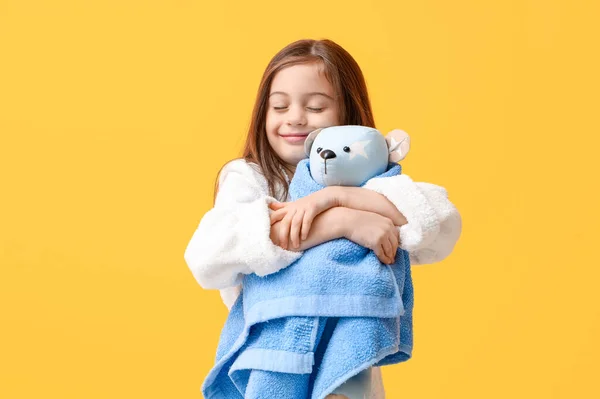 黄色の背景にテディベアとタオルでバスローブでかわいい小さな幸せな少女 — ストック写真