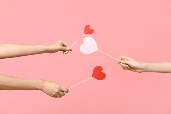 Руки женщины держат бумажные сердца на розовом фоне. Празднование Дня Святого Валентина