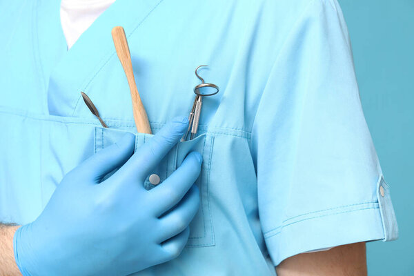 Dentist with dental tools in pocket on blue background, closeup. World Dentist Day