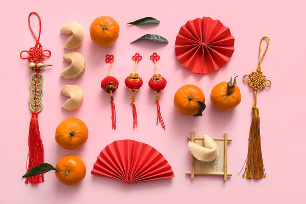 Состав с бумажными вентиляторами, мандаринами и китайскими символами на розовом фоне. Новогодний праздник
