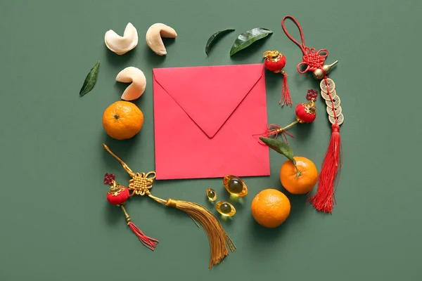 Composition with red envelope, tangerines and Chinese symbols on green background. New Year celebration