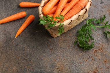 Siyah arka planda taze havuç dolu bir sepet.