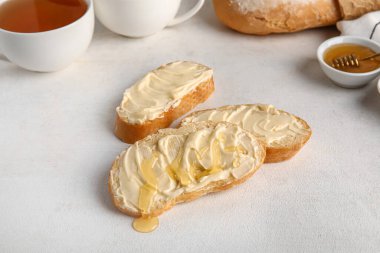 Beyaz arka planda tereyağlı ve bal dolu lezzetli ekmek.