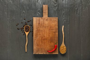 Boş kesim tahtasıyla kompozisyon ve koyu ahşap arka planda baharatlar