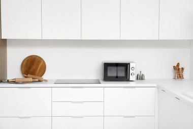 Mikrodalga fırını, elektrikli soba ve beyaz tezgahlı mutfak malzemeleri.