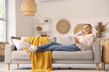 Tablet bilgisayar evde kanepede kullanan genç adam