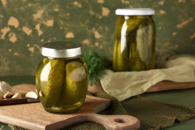 Yeşil duvarın yanındaki masada lezzetli salatalıklı kavanozlar.