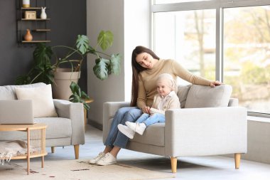 Küçük kız kemoterapiden sonra annesi evdeki kanepede oturuyor.