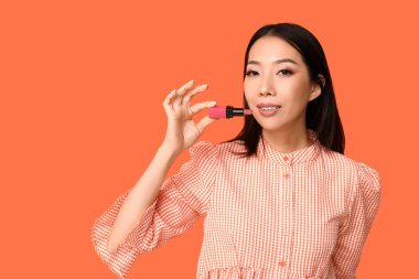 Turuncu arka planda ruj izi olan güzel bir Asyalı kadın.