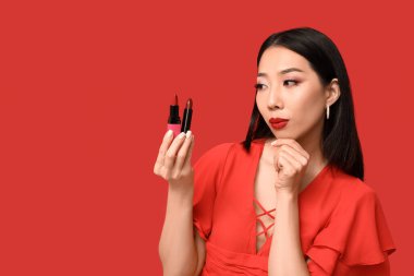 Kırmızı arka planda ruj izi olan düşünceli Asyalı kadın.