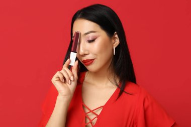 Kırmızı arka planda ruj izi olan güzel Asyalı kadın.