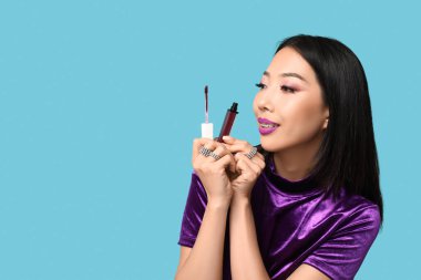 Mavi arka planda sıvı ruju olan güzel bir Asyalı kadın.