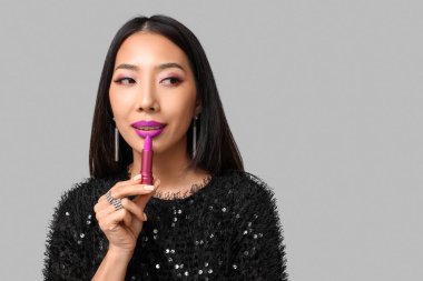 Gri arkaplanda ruj izi olan güzel bir Asyalı kadın.