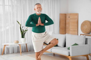 Sportif olgun adam evde yoga yapıyor.