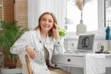 Kadın kuyumcu atölyede masada oturuyor.