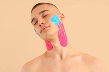 Yüzünde bej arkaplan bandı olan genç bir adam, yakın plan.