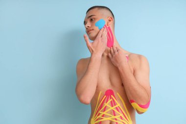 Mavi arka planda fizyobandı olan genç bir adam.