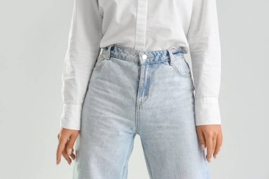 Hafif arka planda modaya uygun kot giyen genç kadın, yakın plan.