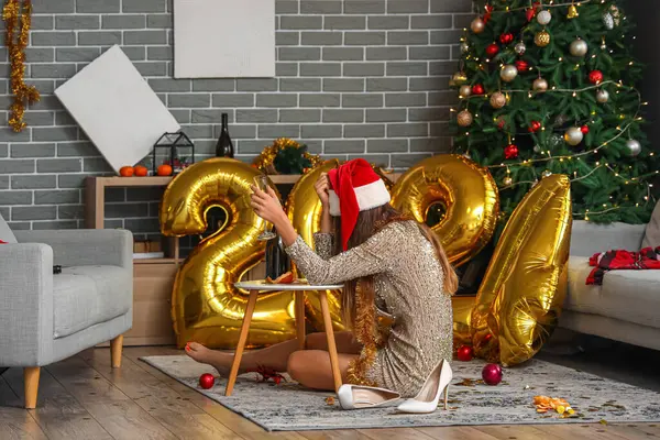 Drunk woman sitting in messy living room after New Year party