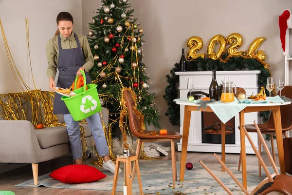 Female janitor cleaning in messy living room after New Year party