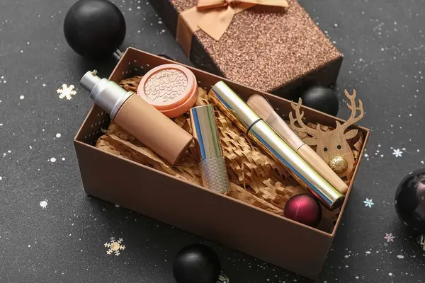 Gift box with different makeup products  on dark background, closeup