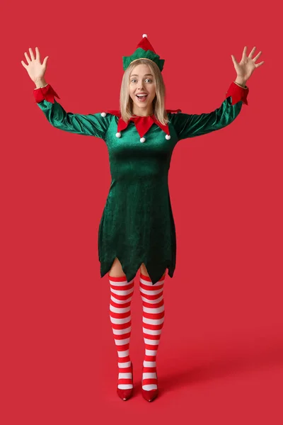 Emotional young woman in elf costume on red background
