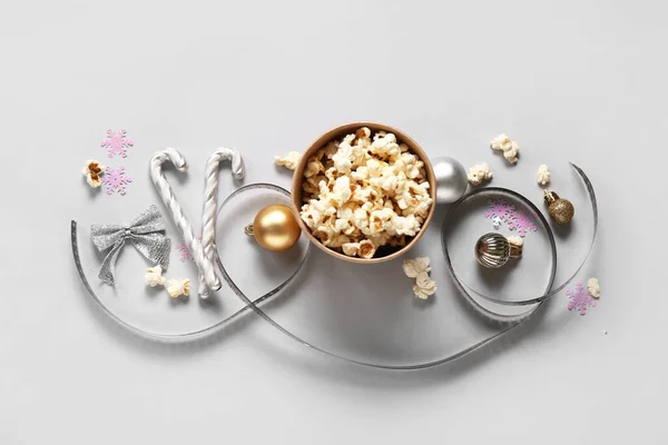 Bucket of popcorn with film reel and Christmas decor on white background