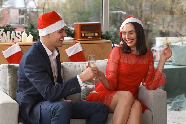 Young couple in Santa hats drinking champagne at New Year party