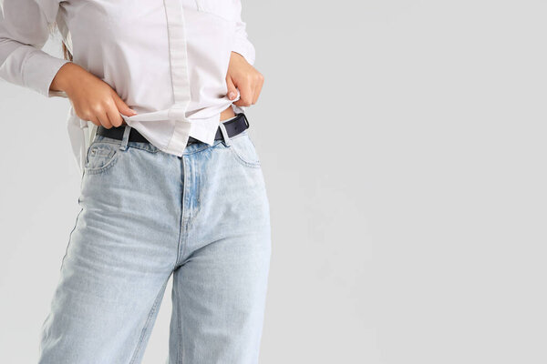 Молодая женщина в модных джинсах на светлом фоне, крупным планом