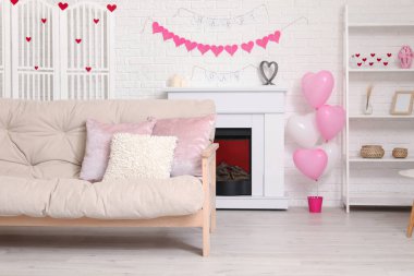 Beyaz kanepeli, şömineli ve Sevgililer Günü kutlaması için dekorlu festival salonu.