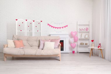 Beyaz kanepeli, şömineli ve Sevgililer Günü kutlaması için dekorlu festival salonu.