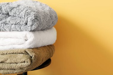 Sarı duvarın yanındaki sandalyeye yeni katlanmış battaniyeler, yakın plan.