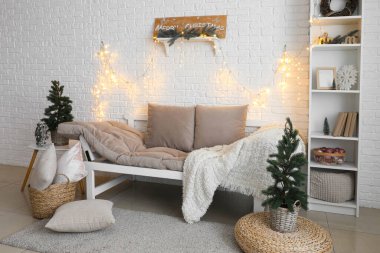 Oturma odasının içinde Noel ağaçları, kanepe ve parlayan ışıklar var.