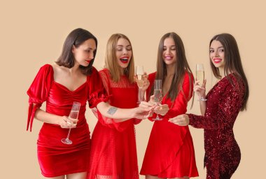 Şampanya kadehleri ve havai fişeklerle güzel, mutlu genç kadınlar Noel 'i bej arka planda kutluyor.