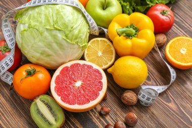 Farklı sağlıklı ürünlere sahip kompozisyon ve ahşap arka planda ölçüm bandı, yakın plan