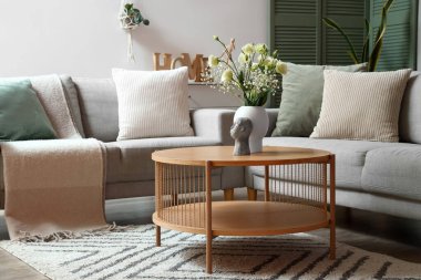 Gri kanepeleri, kahve masasında vazosu ve çiçekleri olan modern oturma odasının içinde.