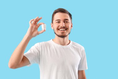 Mavi arka planda plastik dişli yakışıklı bir genç. Diş sağlığı konsepti