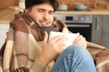 Evde sıcak ekose kumaş ve dokuları olan genç bir adam, yakın plan.