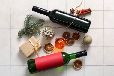 Kurumuş portakallı şarap şişeleri, farklı baharatlar ve beyaz fayanslı Noel hediyesi kutusu.