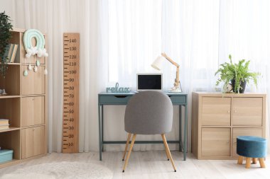 Rahat çalışma alanı, dizüstü bilgisayarı ve ahşap stadyumu olan modern çocuk odası.