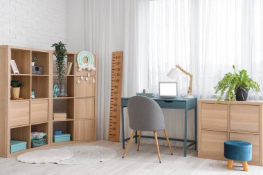 Rahat çalışma alanı, dizüstü bilgisayarı ve ahşap stadyumu olan modern çocuk odası.